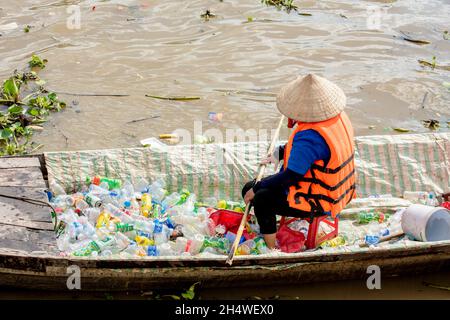 Les travailleurs pauvres ramassant des bouteilles en plastique qui polluent l'environnement sur le fleuve au Vietnam Banque D'Images