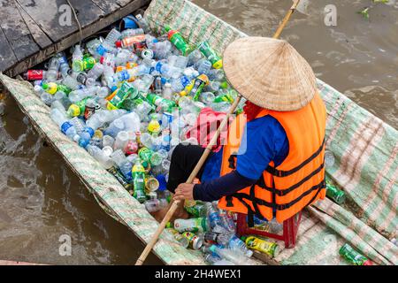 Les travailleurs pauvres ramassant des bouteilles en plastique qui polluent l'environnement sur le fleuve au Vietnam Banque D'Images