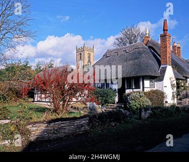 Chalets avec la flèche de l'église Saint-Pierre à l'arrière, Welford-on-Avon, Warwickshire, Angleterre, Royaume-Uni,Europe. Banque D'Images