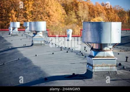 Système de ventilation d'échappement de toit d'air d'un grand bâtiment commercial industriel avec cheminées à capuchon et conduits en rangée sur toit sélectif Banque D'Images