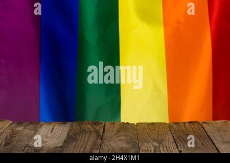 Table en bois rustique vide, avec place vide pour le produit au centre, faite de planches anciennes avec fierté le drapeau arc-en-ciel sur le fond. Banque D'Images