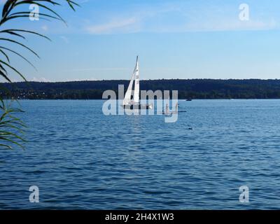 UEBERLINGEN, ALLEMAGNE - 18 septembre 2021 : vue sur le lac de Constance avec voilier et deux pagayeurs en bois Banque D'Images