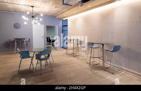 Chaises vides disposées autour des tables sur un plancher de bois dur dans un bureau éclairé Banque D'Images