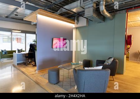 Fauteuils devant la télévision dans le hall d'un bureau moderne éclairé Banque D'Images