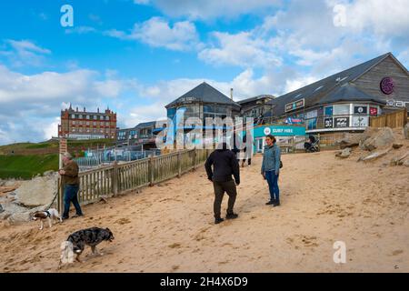 Les gens et leurs chiens marchent sur la plage de Fistral à Newquay, dans les Cornouailles Banque D'Images