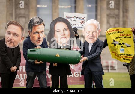 05 novembre 2021, Berlin: Avec les apparences de Christian Lindner (l-r), chef de groupe parlementaire et chef de parti du FDP, Robert Habeck et Annalena Baerbock, les deux dirigeants fédéraux de Bündnis 90/Die Grünen,Et OLAF Scholz, candidat du SPD au poste de chancelier et ministre fédéral des Finances, les membres des organisations de la paix manifestent devant le bâtiment du Reichstag pour une interdiction des armes nucléaires par les Nations unies dans l'accord de coalition.Ils détiennent une bombe symbolique.La protestation vise les partis SPD, Green et FDP dans les négociations de coalition pour former un nouveau gouvernement fédéral.Photo: Kay Nietf Banque D'Images