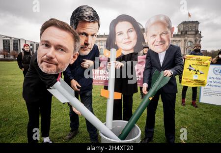 05 novembre 2021, Berlin: Avec les apparences de Christian Lindner (l-r), chef de groupe parlementaire et chef de parti du FDP, Robert Habeck et Annalena Baerbock, les deux dirigeants fédéraux de Bündnis 90/Die Grünen,Et OLAF Scholz, candidat du SPD au poste de chancelier et ministre fédéral des Finances, les membres des organisations de la paix manifestent devant le bâtiment du Reichstag pour une interdiction des armes nucléaires par les Nations unies dans l'accord de coalition.Ils ont placé des missiles symboliques dans un seau.La protestation vise les partis SPD, Green et FDP dans les négociations de coalition pour former un nouveau gouvernement fédéral.Photo: K Banque D'Images