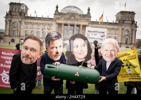 05 novembre 2021, Berlin: Avec les apparences de Christian Lindner (l-r), chef de groupe parlementaire et chef de parti du FDP, Robert Habeck et Annalena Baerbock, les deux dirigeants fédéraux de Bündnis 90/Die Grünen,Et OLAF Scholz, candidat du SPD au poste de chancelier et ministre fédéral des Finances, les membres des organisations de la paix manifestent devant le bâtiment du Reichstag pour une interdiction des armes nucléaires par les Nations unies dans l'accord de coalition.Ils détiennent une bombe symbolique.La protestation vise les partis SPD, Green et FDP dans les négociations de coalition pour former un nouveau gouvernement fédéral.Photo: Kay Nietf Banque D'Images