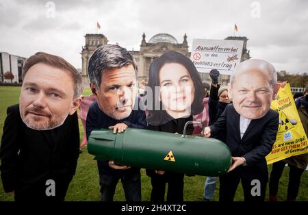 05 novembre 2021, Berlin: Avec les apparences de Christian Lindner (l-r), chef de groupe parlementaire et chef de parti du FDP, Robert Habeck et Annalena Baerbock, les deux dirigeants fédéraux de Bündnis 90/Die Grünen,Et OLAF Scholz, candidat du SPD au poste de chancelier et ministre fédéral des Finances, les membres des organisations de la paix manifestent devant le bâtiment du Reichstag pour une interdiction des armes nucléaires par les Nations unies dans l'accord de coalition.Ils détiennent une bombe symbolique.La protestation vise les partis SPD, Green et FDP dans les négociations de coalition pour former un nouveau gouvernement fédéral.Photo: Kay Nietf Banque D'Images