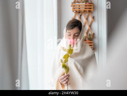 une femme avec haik prend une rose à la main Banque D'Images