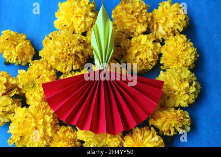 Diwali diya fait avec du papier d'origami et des fleurs marigolées fraîches sur fond bleu Banque D'Images