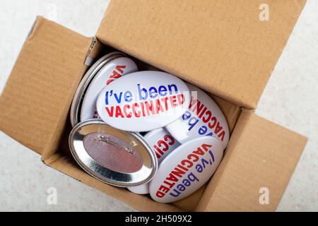 Boutons de campagne de vaccination dans la boîte en carton sur la vue plate de la table légère Banque D'Images