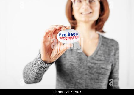 Bouton de campagne de vaccination dans un sourire heureux des doigts de femme caucasienne.J'ai été vacciné texte. Banque D'Images