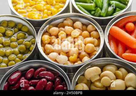 Légumes en conserve dans des boîtes ouvertes sur la table de cuisine. Aliments non périssables à longue durée de conservation Banque D'Images