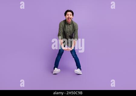 Photo pleine grandeur de drôle funky heureux jeune homme tenir les mains ensemble bonne humeur profiter isolé sur fond violet couleur Banque D'Images