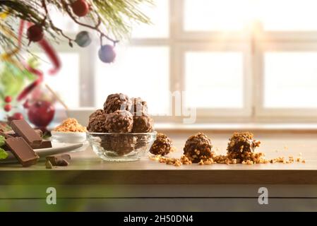 Des boules de chocolat aux amandes sont disposées sur une table décorée pour Noël et une fenêtre en arrière-plan.Vue avant.Composition horizontale. Banque D'Images