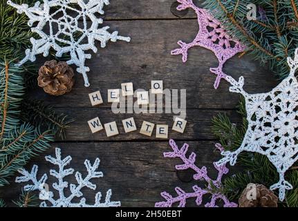 décorations en crochet flocon de neige sur sol en bois avec textes d'hiver et branche de sapin et cônes lettres en bois Banque D'Images