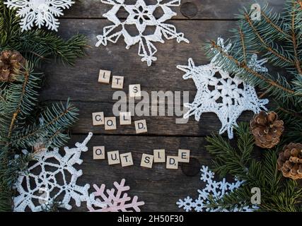 décorations en crochet flocon de neige sur sol en bois avec textes d'hiver et branche de sapin et cônes lettres de bois arrière-plan Banque D'Images