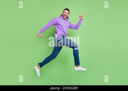 Pleine longueur profil photo de côté de jeune homme stupéfié pressé coureur vente isolé sur fond vert couleur Banque D'Images
