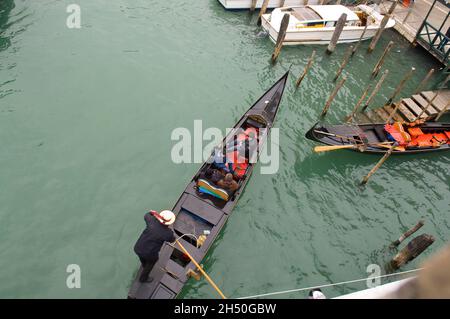 Un Gondolier une gondole de direction parmi les autres bateaux y compris la rivière de bus à Venise, Italie, près de la gare. Banque D'Images