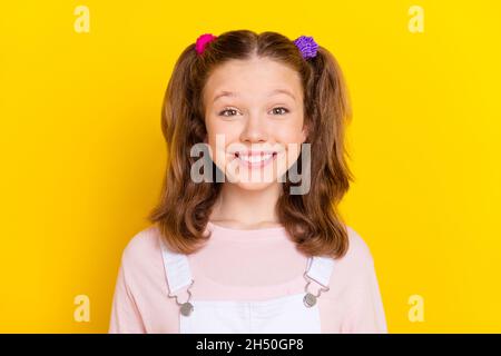 Photo portrait écolière souriante avec queues en blanc général isolé couleur jaune vif arrière-plan Banque D'Images