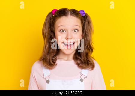 Portrait de photo souriant émerveillé bonne écolière avec queues en blanc général isolé couleur jaune vif arrière-plan Banque D'Images