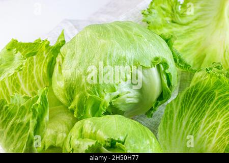 Feuilles de salade de laitue iceberg vert frais coupées sur fond clair sur la table dans la cuisine. Banque D'Images