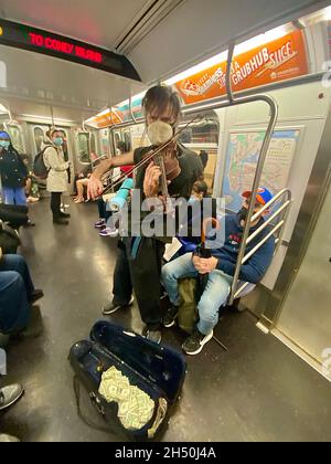Un virtuose inconnu et non lavé se produit sur un train F du centre-ville de Manhattan, New York. Banque D'Images