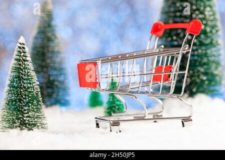 Achats du nouvel an.Un tramway de supermarché se trouve dans la neige, des spruces verts sont autour Banque D'Images