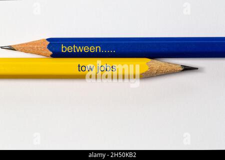 deux crayons aiguisés en bleu et jaune pointent dans différentes directions isolées sur fond blanc avec l'expression: entre les travaux de remorquage Banque D'Images