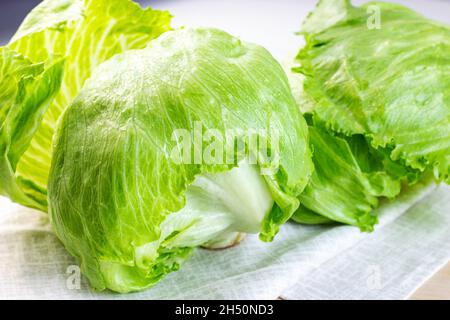 La salade de laitue iceberg verte fraîche laisse sur fond clair sur la table de la cuisine. Banque D'Images