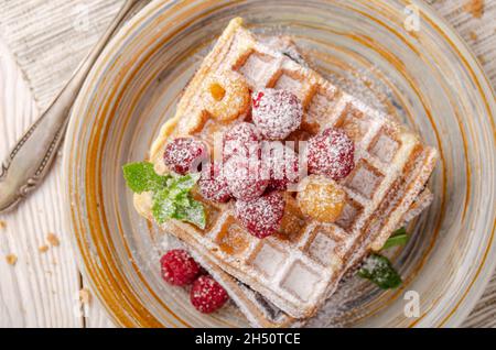 Profitez d'une vue imprenable sur les gaufres belges servies avec des framboises et feuille de menthe saupoudrée de sucre en poudre Banque D'Images