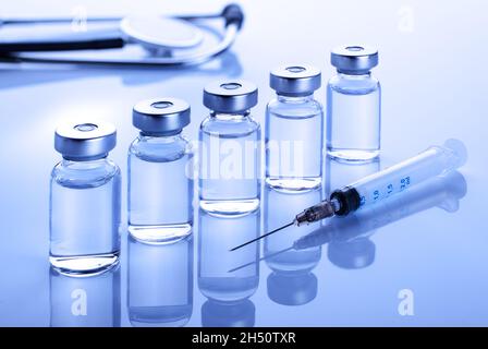Flacons avec médicament liquide comme vaccin dose vaccin vaccin vaccin vaccin contre la grippe avec stéthoscope, seringue pour traitement par injection sur table médicale. Vaccination ou immunisation Banque D'Images