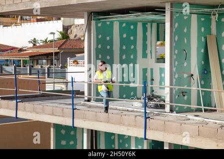 Femme architecte ou superviseur debout sur un balcon inachevé d'un bâtiment moderne en construction portant un gilet haute visibilité et des bottes de sécurité Banque D'Images