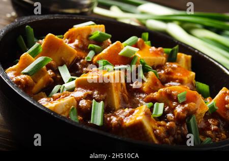 Mapo tofu dans une poêle en fonte avec ciboulette hachée de porc sauce soja poivre du sichuan ail et épices Banque D'Images