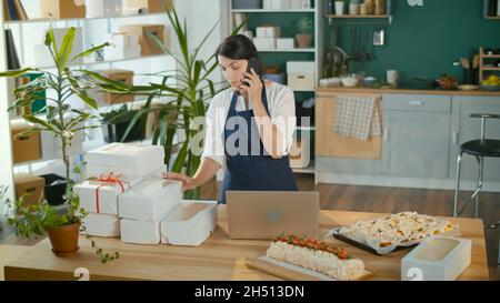 Une femme d'affaires prospère gérant ses travaux d'affaires dans une cuisine confortable Banque D'Images