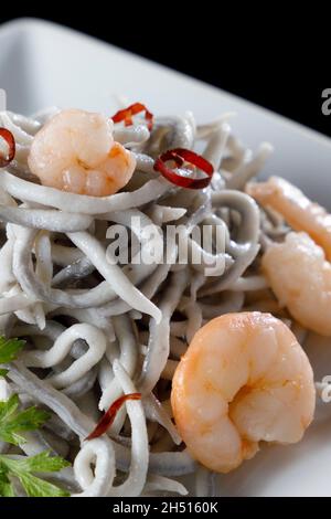 Portion de gluttonie avec crevettes et piments sur une surface noire brillante Banque D'Images