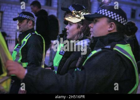 Westminster, Londres, Royaume-Uni.5 novembre 2021.Une jeune femme est emmenée par la police après avoir apparemment essayé de faire des feux d'artifice.Les manifestants de la Marche annuelle du million Mask se mélangent avec les manifestants anti-Lockdown et anti-vaccination, certains aussi dans les masques Guy Fawkes, sur la place du Parlement à Westminster cet après-midi et soir.Des fusées éclairantes et des feux d'artifice sont allumés, ce qui incite la police à prendre une position prudente avec une forte présence policière dans tout Westminster ce soir.Credit: Imagetraceur/Alamy Live News Banque D'Images