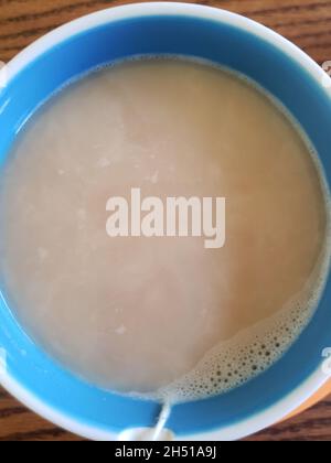 Tasse de thé noir avec crème dans un mug bleu Banque D'Images