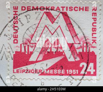 ALLEMAGNE, DDR - VERS 1951 : timbre-poste de l'Allemagne, RDA montrant une marque « M » devant une usine industrielle.Foire de printemps de Leipzig 1951 Banque D'Images