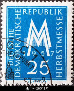 ALLEMAGNE, DDR - VERS 1957 : timbre-poste de l'Allemagne, RDA montrant MM le symbole du salon de l'automne de Leipzig en 1957. Bleu Banque D'Images