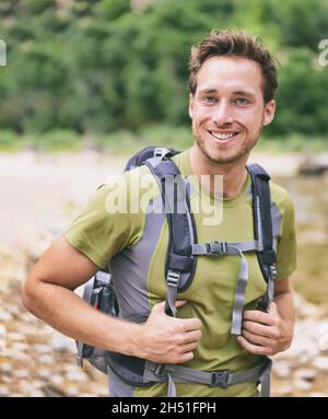 Active jeune homme portrait randonnée à l'extérieur.Jeune randonneur homme souriant heureux porter un sac à dos pour faire du sac à dos camping voyage à l'extérieur pendant la randonnée Banque D'Images