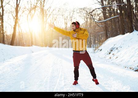 Homme Motinvated dans les vêtements de sport échauffer les muscles, écouter de la musique, se préparer à la compétition sportive Banque D'Images