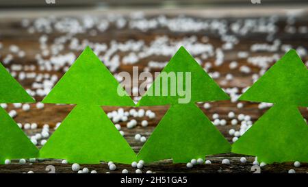 Arbres en papier vert sur fond de bois rustique recouvert d'un peu de blanc comme des boules de neige et avec espace de copie Banque D'Images