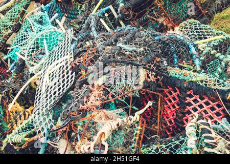 Pile désordonnée de pièges à homard aux couleurs vives et de filets fantômes - débris marins Banque D'Images