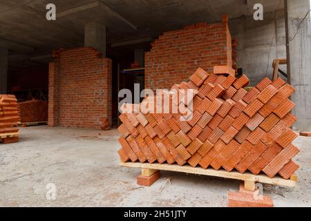 Briques de construction rouges.Brique sur une palette sur un chantier de construction.Matériaux de construction pour la construction de murs et de cloisons dans le bâtiment. Banque D'Images