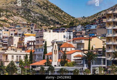 Saranda, Albanie - 14 mai 2021 : vue sur les maisons de la ville de Saranda et le clocher de l'église d'Ortodox sur fond de montagnes Albanina. Banque D'Images