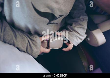 Fixation de passager portant la ceinture de sécurité dans un avion pour sauver la vie en volant dans le ciel.Concept de sécurité et de voyage. Banque D'Images