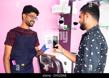 Client scannant le code QR dans smartphone pour faire le paiement à baber à la boutique de coiffure - concept de paiement numérique, technologie sans espèces, recommander E Banque D'Images