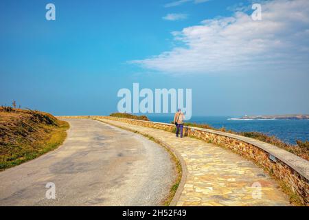 Un homme marche le long de la promenade Lighthouse Road (Estrada do faro) le long de la mer par une journée ensoleillée Banque D'Images